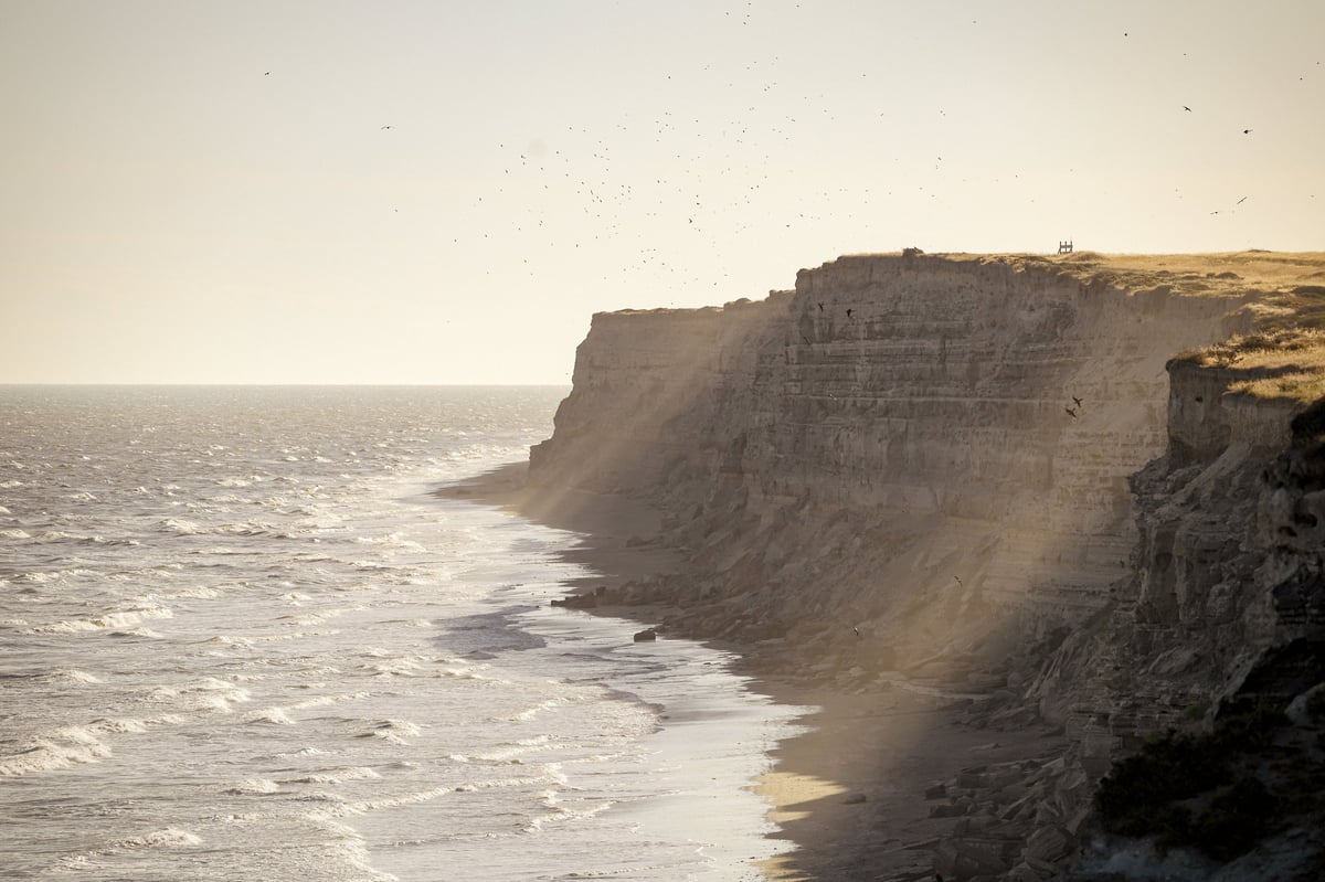 Beach with rocky cliffs and ocean waves at sunset