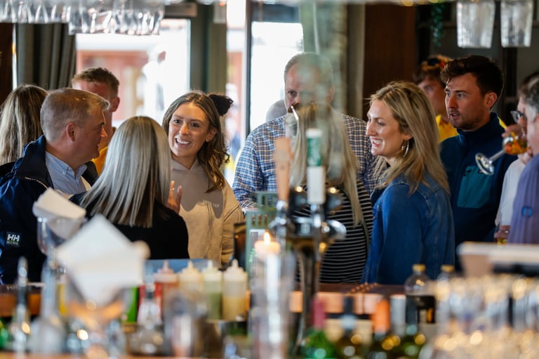 Group of people socializing at a bar counter with bottles and glasses