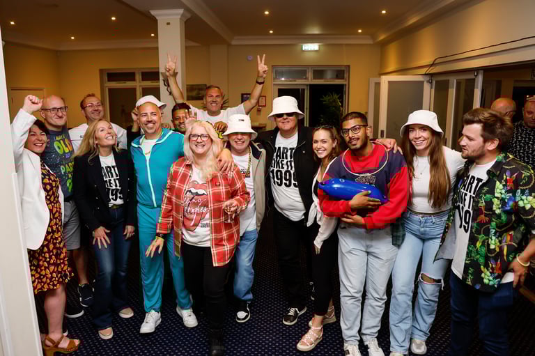 Large group of people wearing white hats gathered together indoors for a celebration or party, smiling at the camera
