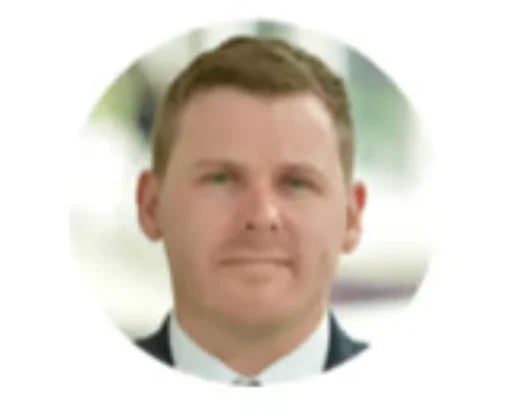 Professional headshot of a middle-aged man in business attire against a blurred background